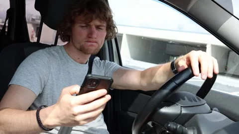 Driver constantly checks smartphone while driving and loses focus on traffic Stock Footage 343719854