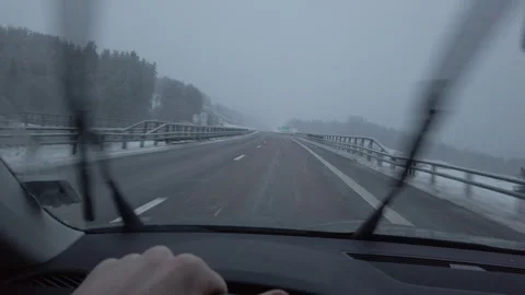 Driver controlling steering wheel driving highway snowy weather Stock Footage 287636475