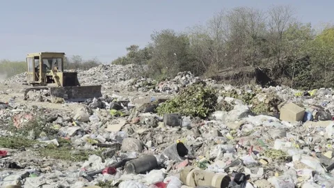 Driver of crawler excavator scooping pile of junks to the landfill downhill. Stock Footage 82202062