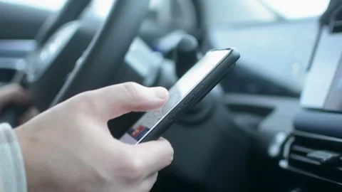Driver dangerously uses smartphone while driving, diverting attention from road Stockbeeldmateriaal 320896727