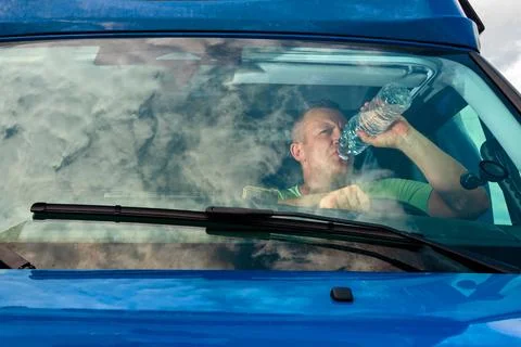 Driver drinking water from bottle in van cabin 写真素材