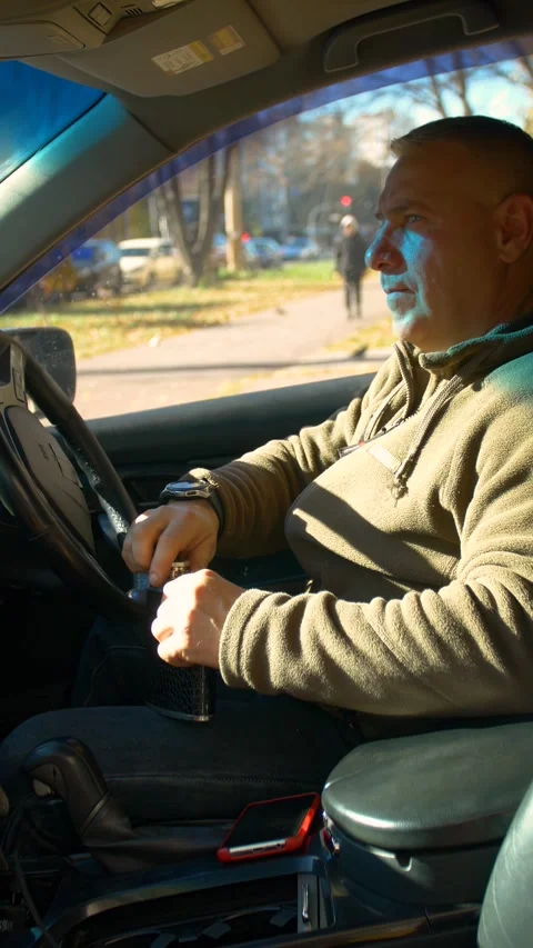 The driver drinks strong alcohol while driving - vertical video. Stock Footage 320357346