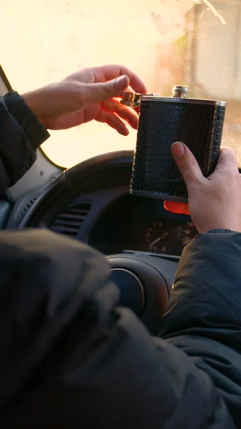 The driver drinks strong alcohol while driving - vertical video. Stock Footage 320357416