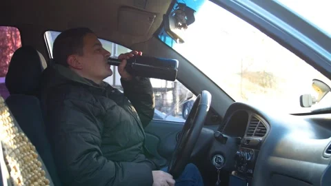 The driver drinks strong alcohol while driving. Drunk driving. Stock Footage 320382355