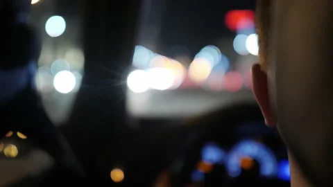 A driver driving a car against the background of a night road and the glare of 库存影片 133486943
