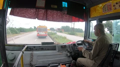 A driver is driving a commuter bus on the clear highway in India. Stock Footage 138377333