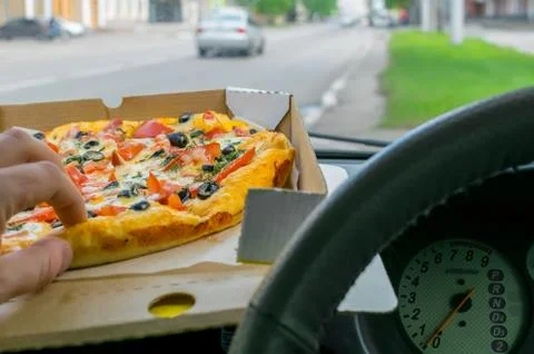 Driver eats pizza in the car Stock Photos