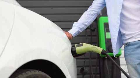 The driver of the electric car inserts the electrical connector to charge the Stock Footage 251763278