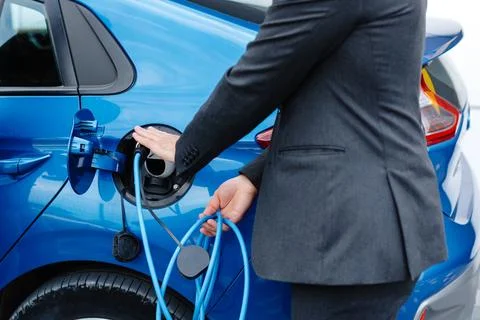 The driver of the electric car inserts the electrical connector to charge t.. Stock Photos