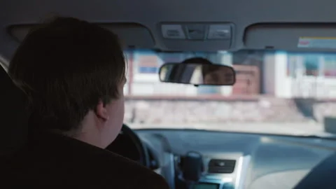 Driver engages with passenger while navigating urban streets in daylight Stock Footage 309740042