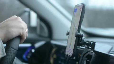 Driver follows navigation route using smartphone mounted in car, focusing on Stock Footage 320896717