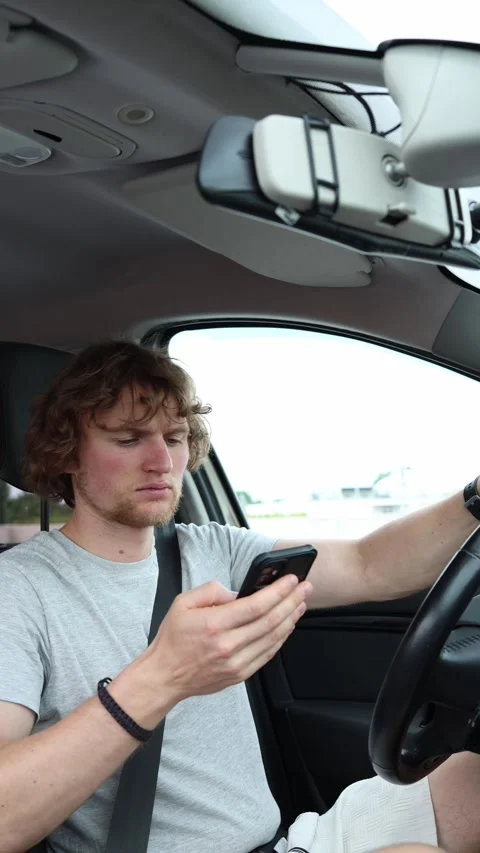 Driver frequently checks his smartphone instead of watching city traffic Video stock 342924136
