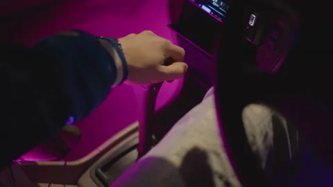 Driver grips gearshift confidently in illuminated city highway scene, Leather Stock Footage 330955677
