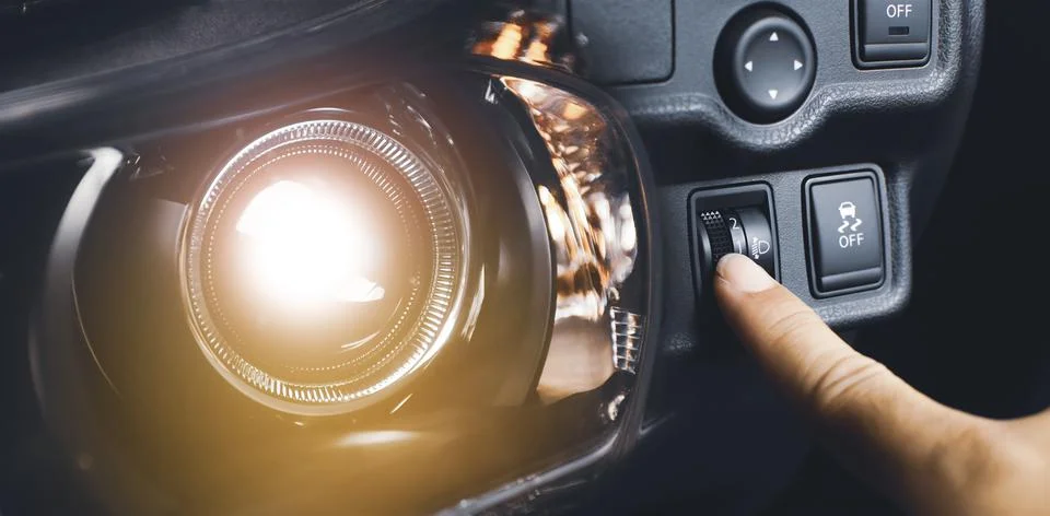 Driver hand adjusting headlight level switch and car headlight bright,Double  Foto stock