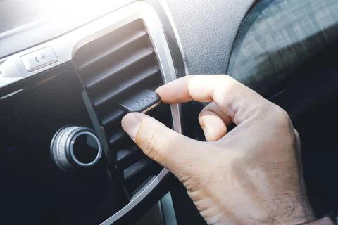 Driver hand adjusting wind direction of air vent on console in the car Stock-Fotos