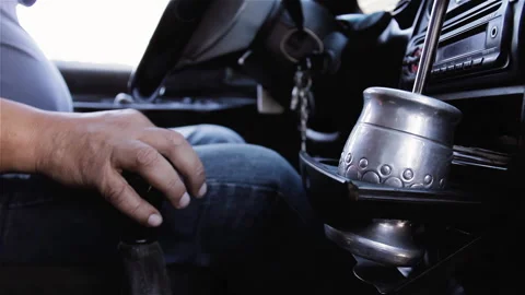 Driver Hand on Gear Shift Next to Traditional Mate Gourd in Vehicle - 4K Stock Footage 337073076