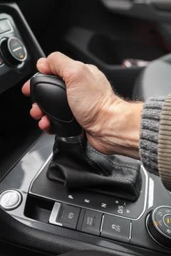 Driver hand holds automatic gear lever Stock Photos