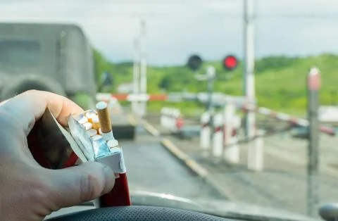 Driver hand with a pack of cigarettes on the steering wheel of the car Foto stock