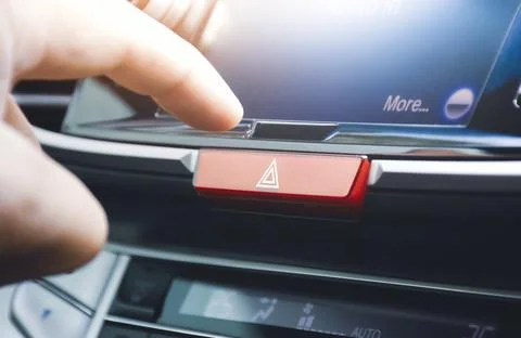 Driver hand pressing hazard light button switch on dashboard in the car Stock-Fotos