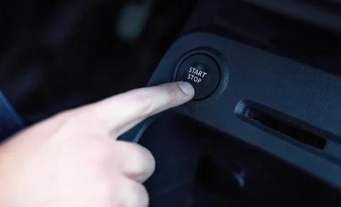 Driver hand pushes engine start stop button. Foto stock