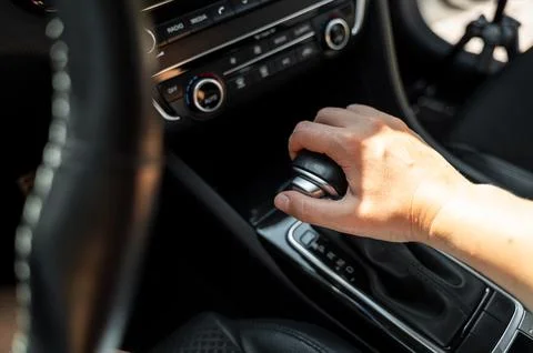 Driver hand rests on gear shift of automatic transmission in car Stock Photos