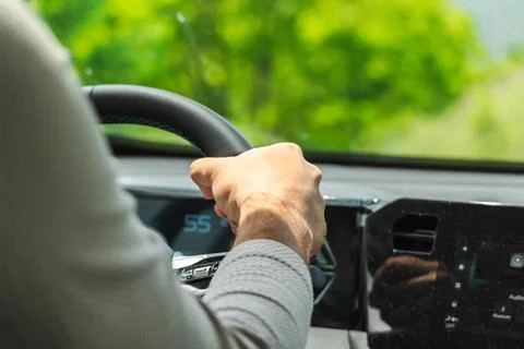 Driver hand on steering wheel during scenic road trip through countryside Stock Photos