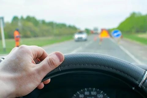 Driver hand on the steering wheel inside the car on the background of the road Stock Photos