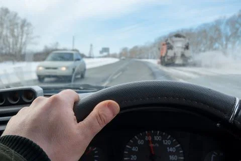 Driver hand is on the steering wheel inside the car Stock Photos