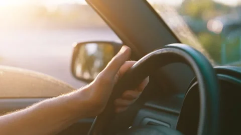 Driver hand tapping fingers on steering wheel stuck in traffic jam sunset golden Stock Footage 314687215
