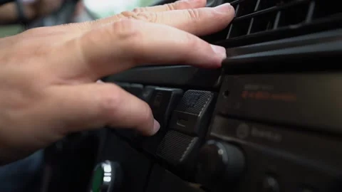 Driver hand tuning air ventilation grille on black plastic retro car dashboard Stock Footage 168897312