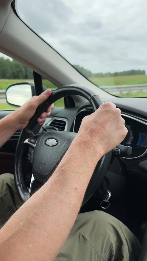 Driver hands holding steering wheel while driving car on highway road. Clos.. Stock Footage 345528162