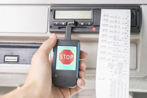 Driver holding a digital tachograph reader with big red stop mark on the screen Foto stock