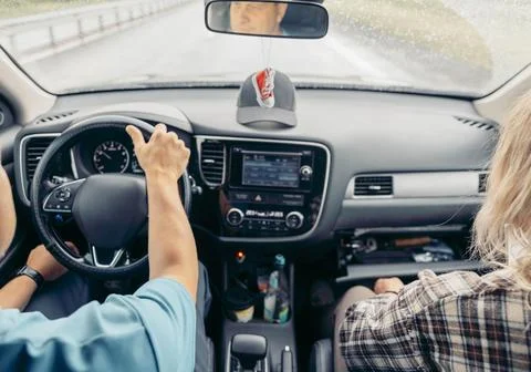 Driver holding steering wheel inside modern car while passenger sits in front Stock Photos