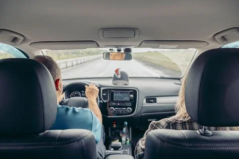 Driver holding steering wheel inside modern car while passenger sits in front Stock Photos