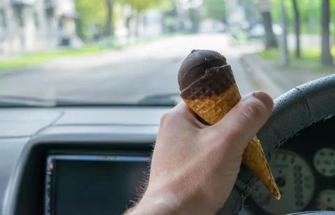 The driver holds the ice cream while driving a car Stock Photos