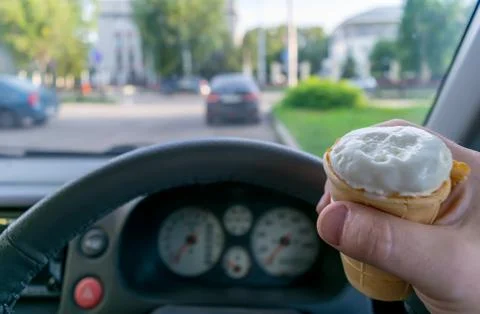 The driver holds the ice cream while driving a car Stock Photos