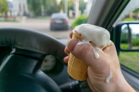 The driver holds the ice cream while driving a car Stock Photos