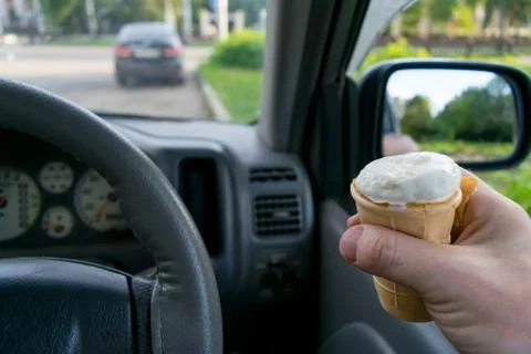 The driver holds the ice cream while driving a car Stock Photos