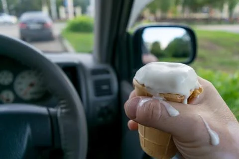 The driver holds the ice cream while driving a car Stock Photos