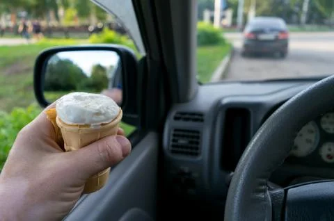 The driver holds the ice cream while driving a car Stock Photos