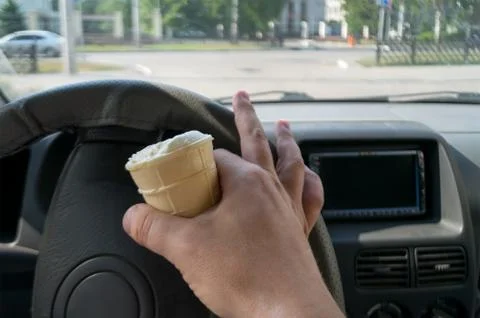 The driver holds the ice cream while driving a car Stock Photos