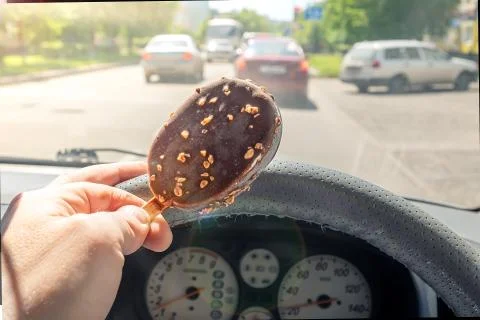 The driver holds the ice cream while driving a car Stock Photos