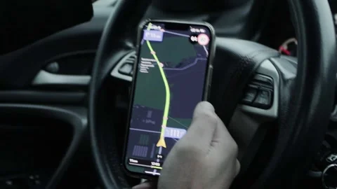 The driver holds a smartphone with a navigator against the background of the Video stock 243161858