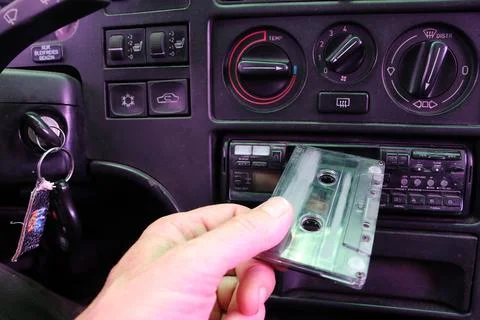 The driver inserts a cassette into a cassette recorder in an old car. Stock Photos