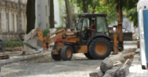 Driver inside of Cabin of Yellow Excavator Machine Turns Buildings Workers in Stock Footage 54219242