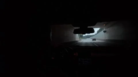 Driver inside SUV leaving tunnel toward bright open road, focused commute view Stock Footage 339886145