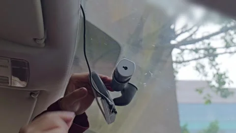 The driver installs a dash cam on the windshield. Stock Footage 329166433