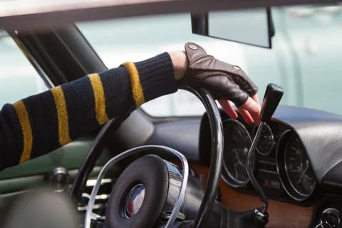 Driver keeps hands on steering wheel of his vintage car Stock Photos