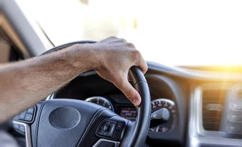Driver keeps his hands on the steering wheel of the car. Stock Photos