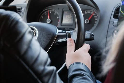 Driver in a leather jacket confidently holding the steering wheel, dashboar.. Фото